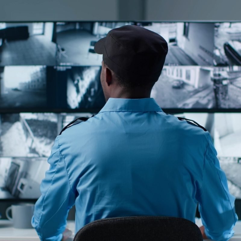 Back,View,Of,African-american,Security,Operator,Use,Computer,With,Screens